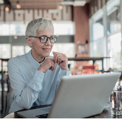 happy mature woman sitting at a laptop in a coffee shop